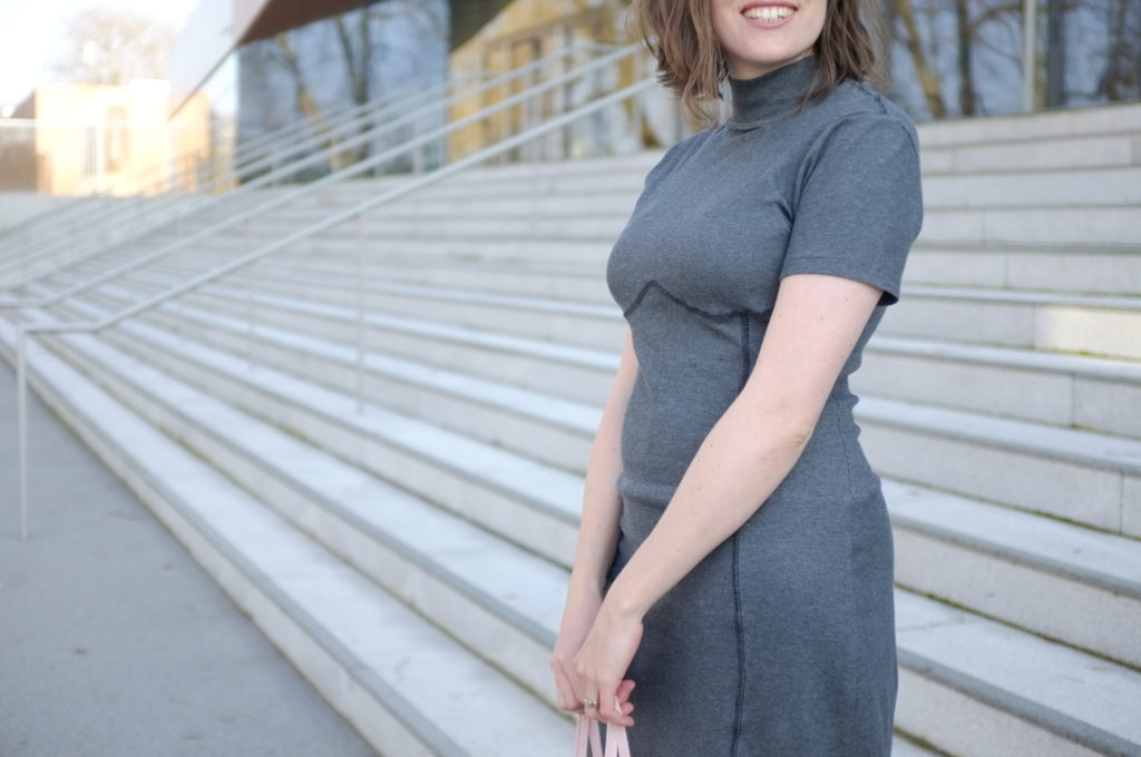 Close-up of a person wearing a grey rib knit dress, shown from mouth to the thighs.